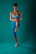 © qunica.com - Fit Female Demonstrating Body Transformation and Muscle Strengthening Exercises in Turquoise Studio