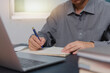 © khunkornStudio - man hands with pen writing on notebook in the office.learning, education and work.writes goals, plans, make to do and wish list on desk..