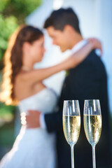 Wall Mural - Champagne, happy couple and blurred embrace at wedding with love, smile and commitment at reception. Wine glasses, woman and man hugging at marriage celebration event, partnership and future together