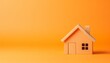 Toy wooden house on orange background. Conveying real estate concept.