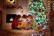 © famveldman - Child at Christmas tree. Kids at fireplace on Xmas