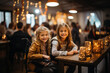© Tatyana - Two girls are sitting in a decorated cafe hall and smiling while looking at the camera. Holiday mood concept.