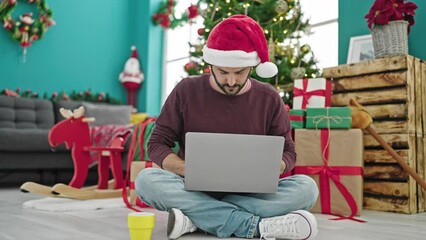 Sticker - Young hispanic man using laptop drinking coffee celebrating christmas at home