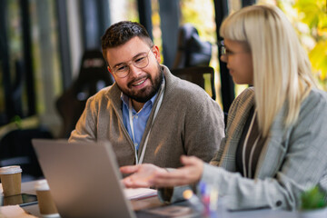 Businessman and businesswoman in meeting using laptop and discussing business strategy. Business coworkers working together in the office.