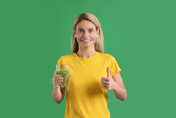 Poster - Woman with glass of tasty celery juice on green background