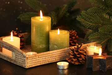 Wall Mural - Christmas composition with burning candles and fir branches on dark background.