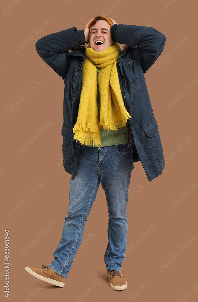 Young man in winter clothes on brown background