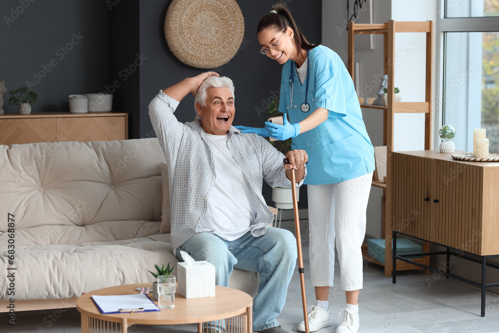 Nurse showing mobile phone to senior man with stick at home