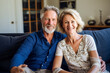© Hunman - Cheerful mature couple sitting on sofa at home.