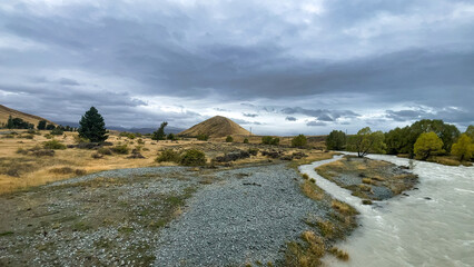 Wall Mural - Flooded stream on the winding narrow gravel road between Lake Tekapo and Lake Pukaki in rural agricultural land