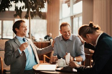 Wall Mural - Businessmen sitting in cafe together laughing