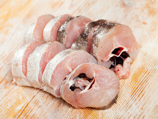 Wall Mural - Fresh raw sliced whiting fish ready for cooking on wooden background..