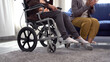 Wheelchair with legs paralysis patient elderly woman sitting talk friend in living room at home. Paralyzed grandmother problem legs sitting on wheelchair conversation friend visit support at room.
