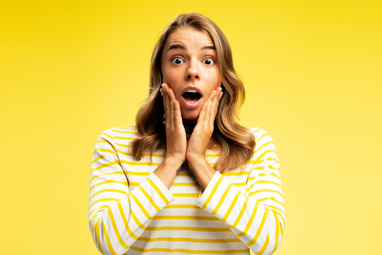 Shocked young woman looking at camera isolated on yellow background. Black Friday shopping concept