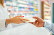 © ADDICTIVE STOCK - Woman giving product to customer in drugstore