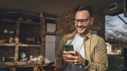 one adult man in front house in day use smart phone video call or sms