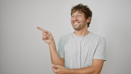 Sticker - Cheerful young man pointing to the side, sporting a t-shirt and confident smile. striking a pose for the camera against an isolated white background. perfect for presenting any product.