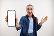 Surprised young woman showing smartphone in hand on white background, selective focus. Mockup for design