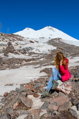 Wall Mural - Girl sitting on the rock overlooking Elbrus mountain, Russia