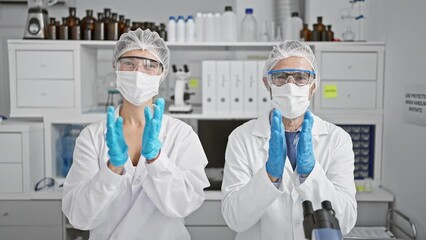 Canvas Print - Two zealous scientists in medical masks and gloves applauding breakthrough in corona research at indoor lab