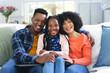 © wavebreak3 - Portrait of happy african american family sitting on couch at home, copy space