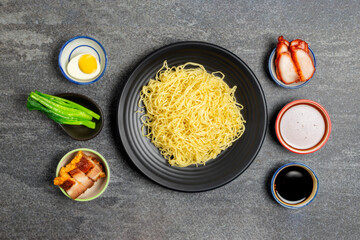 Canvas Print - Noodles and pork soup with pork, barbecue eggs, crispy pork, dumplings, green vegetables with seasonings, healthy food, Thai, Chinese, Hong Kong, arranged on the table, top view.