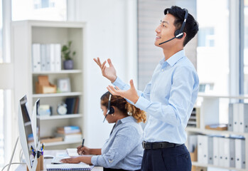 Wall Mural - Customer service, man and standing for consulting in call centre with headset, talking and hand gestures. Telemarketing, asian person or financial advisor and employee, computer or happy for helping