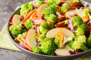 Wall Mural - Vegan low carb diet broccoli, pecans, cranberries, carrots and apples salad with delicious flavors and textures closeup on the plate on the table. Horizontal