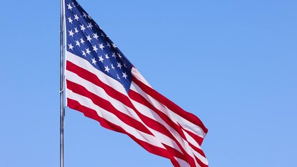 Wall Mural - us flag on a flagpole blowing in the breeze.