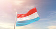 Luxembourg national flag waving in beautiful sky. The symbol of the state on wavy silk fabric.