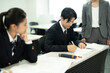 © Paylessimages - 教師と教室で勉強している制服の高校生