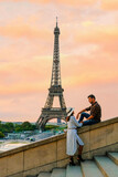 Fototapeta Paryż - Young couple by Eiffel Tower at Sunrise, Paris Eifel Tower Sunrise man woman in love, valentine concept in Paris the city of love. Men and women visiting the Eiffel Tower at sunrise
