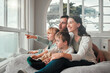 Parents, children and relax by window, happy and pointing with view, bonding and love with in family house. Father, mother and kids with conversation, talking and smile on bean bag, wow face and home