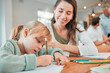 © K Davis/peopleimages.com - Mom, girl and writing for homework with book, development and studying with advice, pencil and smile. Education, mother and daughter with cheers for assessment, progress and growth in family house