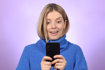 portrait of a young surprised woman with a smartphone in her hands