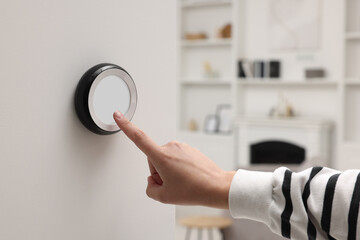 Canvas Print - Woman adjusting thermostat on white wall indoors, closeup. Smart home system