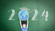 2024 educational academic new year calendar for school class with student kid raising world global planet on teacher's green chalkboard for back to school celebration, classroom schedule concept
