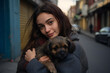 Portrait of a young woman hugging a dog outdoor in street 