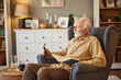 © Stockphotodirectors - Elderly man sitting in armchair and reading a book at home