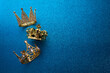 Epiphany Day or Dia de Reyes Magos concept. Three gold crowns on blue sparkling background