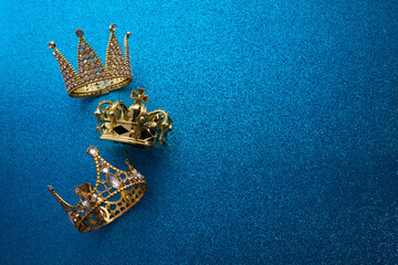 Poster - Epiphany Day or Dia de Reyes Magos concept. Three gold crowns on blue sparkling background