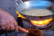 Boiling Roasted Peanut in Syrup in a Wok on a Thai Traditional Stove with a Hand Holding a Brush on the Foreground