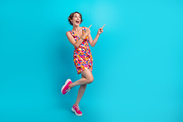 Poster - Full length photo of impressed pleasant girl wear colorful dress indicating look at sale empty space isolated on blue color background