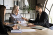 © fizkes - Positive successful elder businesswoman shaking hand to younger best worker man on corporate meeting. Happy diverse managers working on business collaboration, teamwork, partnership