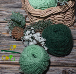 Wall Mural - green wool  yarns in basket and on the wooden table, crochet markers,decoraive christmas branch.