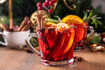 Wall Mural - Traditional Christmas aromatic mulled wine cocktail, red wine grog tea drink with spices, cinnamon, orange and rosemary sprig, on Christmas New Year decorated wooden cozy background