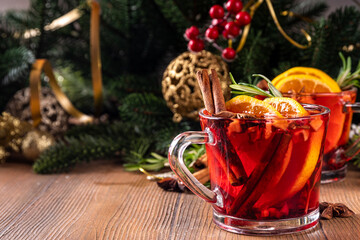 Wall Mural - Traditional Christmas aromatic mulled wine cocktail, red wine grog tea drink with spices, cinnamon, orange and rosemary sprig, on Christmas New Year decorated wooden cozy background