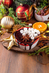 Wall Mural - Winter aromatic hot chocolate cup with Christmas background. Mug of dark hot cocoa drink with cinnamon, anise, spices and marshmallow, on cozy Christmas and New Year holiday decorated background 