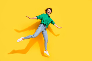 Poster - Full length photo of excited funky girl dressed green shirt jumping high empty space isolated yellow color background