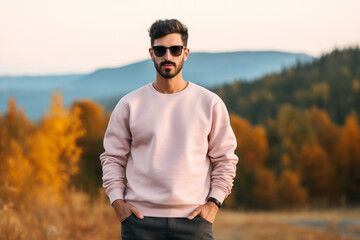 Canvas Print - Man wearing a high-quality Flat Blank Plane crewneck Light Pink color Sweatshirt Mockup with oversized look and sunglasses and nature mountain background